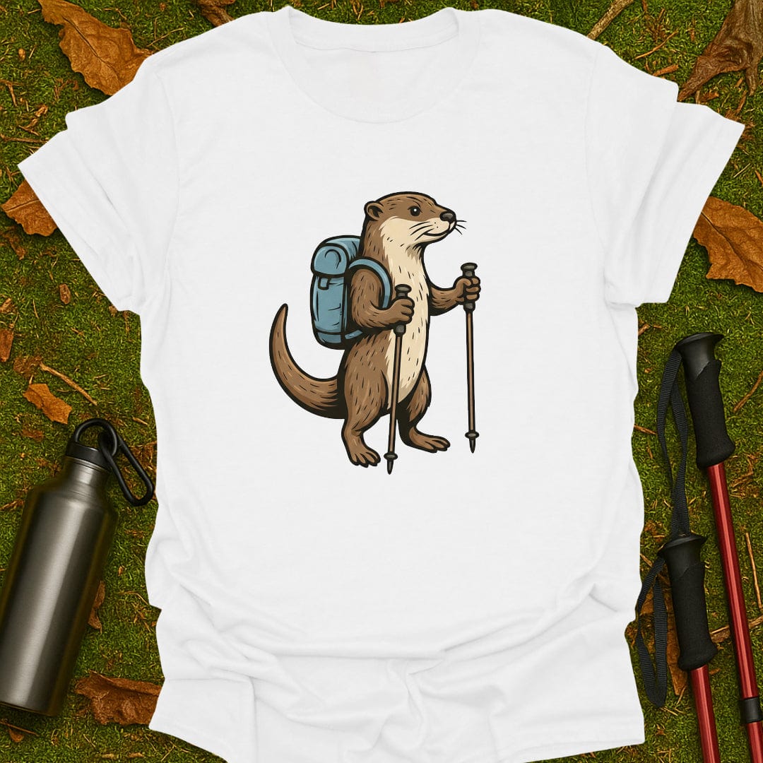 White t-shirt with an otter illustration holding hiking poles and a backpack on a grassy background.