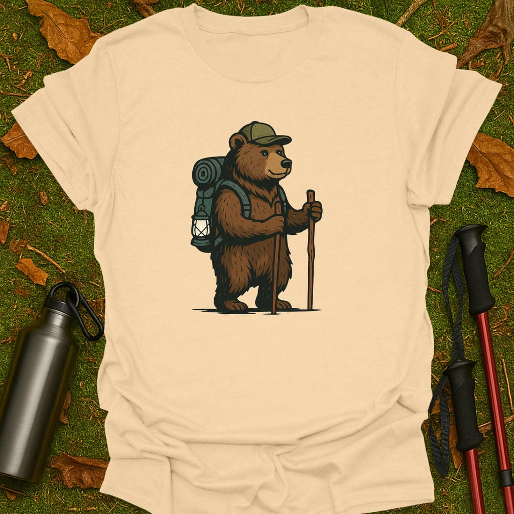 Sand t-shirt with a bear graphic holding a lantern and walking stick on grass.