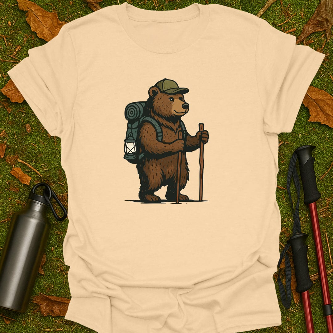 Sand t-shirt with a bear graphic holding a lantern and walking stick on grass.