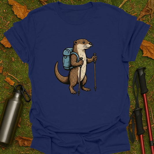Blue t-shirt with an otter wearing a backpack and holding hiking poles on a grassy background.