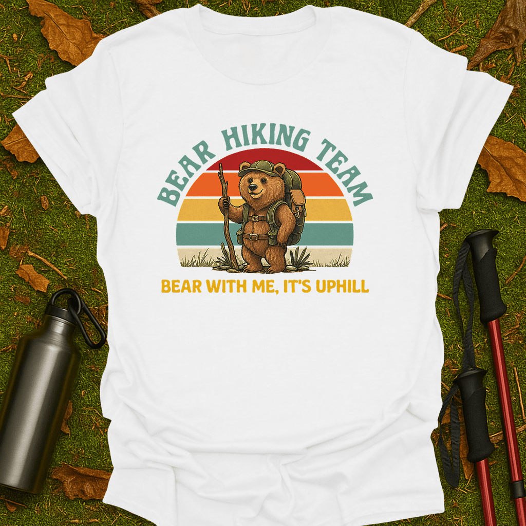 White t-shirt with bear hiking graphic and text on grass with hiking gear.