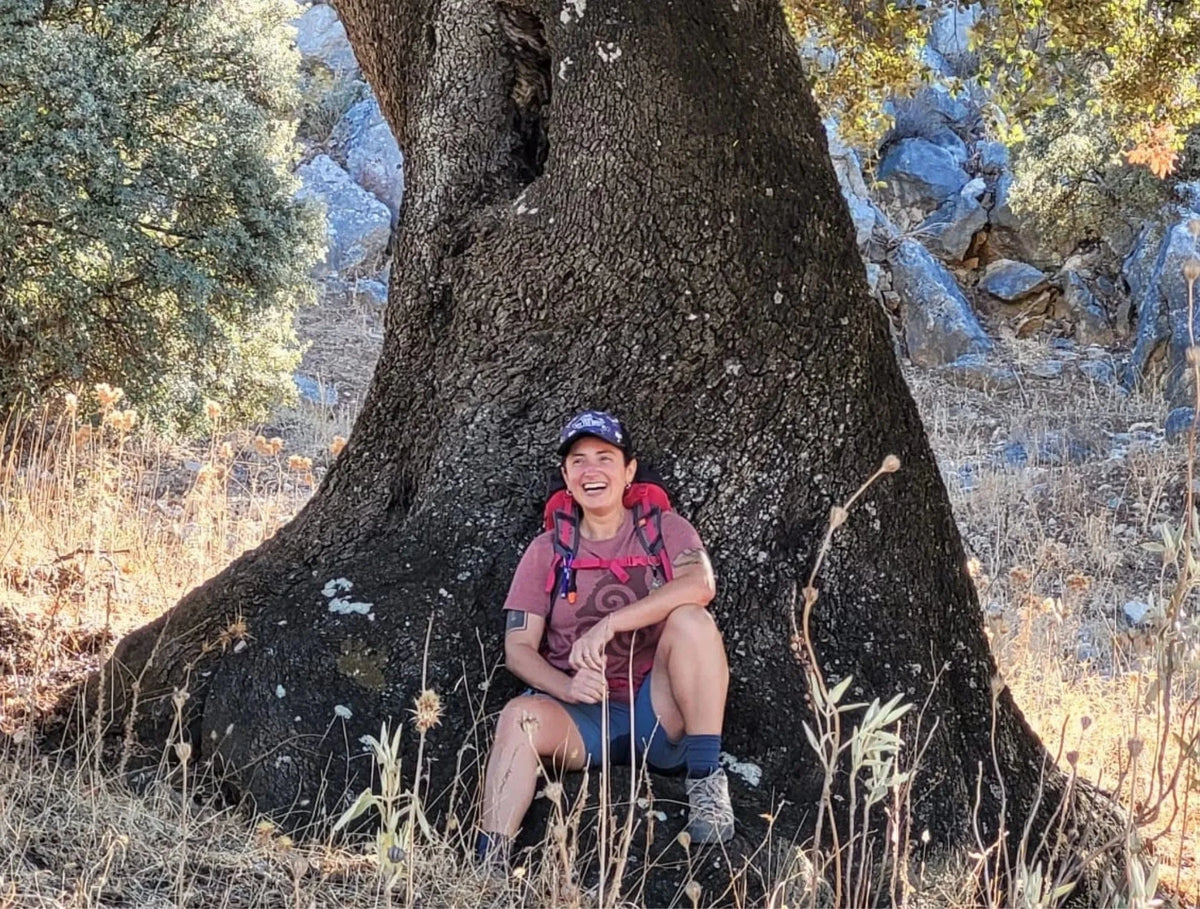 Person sitting under a large tree in a natural setting